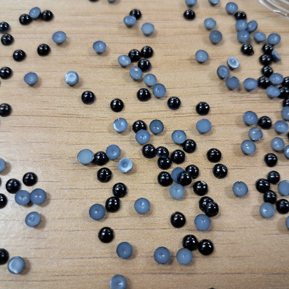 Black flat back pearls for crafting poured out on to a table