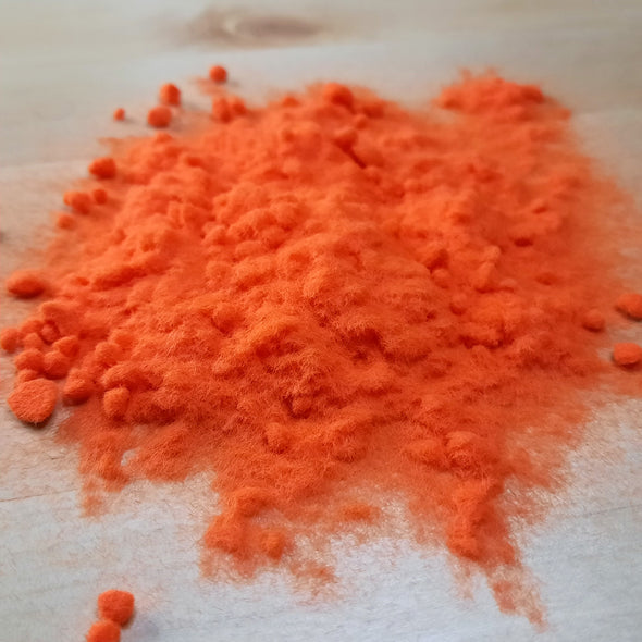 Orange flocking powder poured out on to the table 