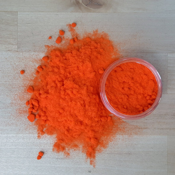 An overhead view of Orange flock poured out on to the table next to the pot