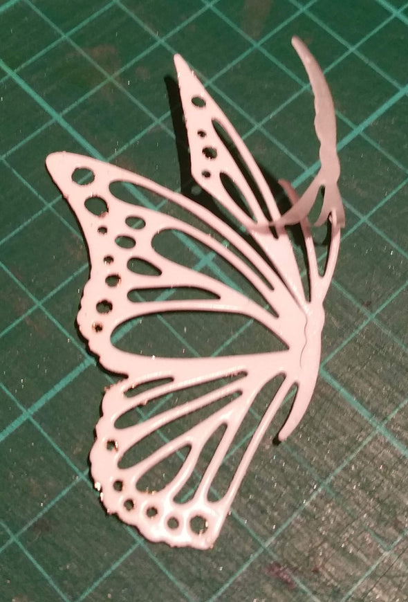 A die cut butterfly covered in Sticky Roll on a cutting mat with part of the liner peeled away